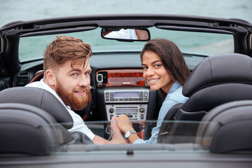 Couple looking back and smiling in white cabriolet