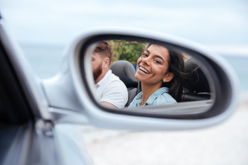Beautiful woman looking at her reflection in a car mirror