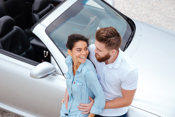 Top view of young couple embracing while standing near car