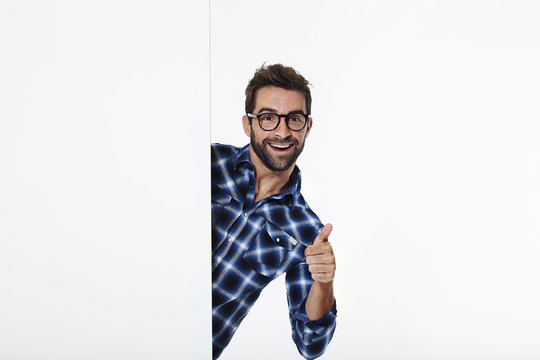 Portrait of man with thumbs up in white studio