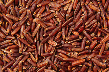 Red rice close-up background. Heap wild brown unpolished rice for vegetarians.