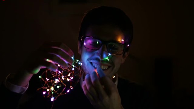 Young boy is playing in his room with the Christmas tree lights in front of his face.