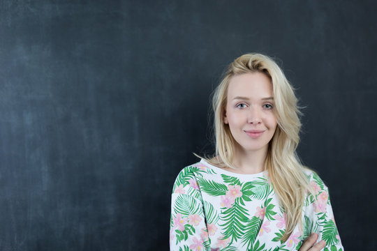 Caucasian woman standing in front of a dark chalkboard.