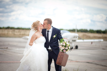 Young couple just married with a suitcase running on aircraft