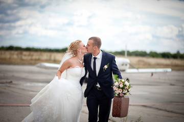 Young couple just married with a suitcase running on aircraft