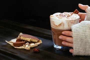 Photo sur Plexiglas Chocolat female hands holding hot drink with chocolate wafers on the black table