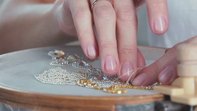 Slow motion. Close-up of mosaic stones diamond embroidery. Master crafts embroider stones with the help of the hoop. Creating jewelry handmade jewelry. Decorative embroidery. White-gold embroidery.