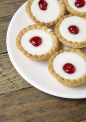 A plate full of freshly baked Bakewell tarts on a rustic wooden table top background