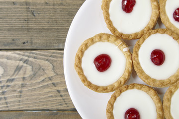 Aerial view of a plate full of freshly baked Bakewell tarts on a rustic wooden table top background