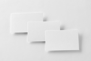 Mockup of three business cards row at white textured paper