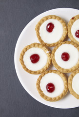 A plate full of freshly baked Bakewell tarts on a rustic slate background