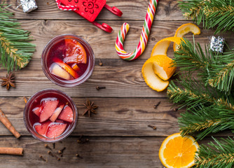 Two glasses of hot mulled wine with oranges, apples and spices