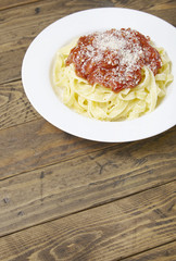 A dinner dish of spaghetti Bolognese on a rustic wooden table top background with blank space below