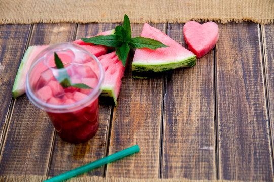 Watermelon cocktail with slice on wooden background. Heart carved from . Top view. Copy space.