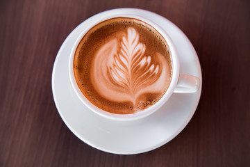 In a special atmosphere, cup of hot, soft latte art on the wooden table in the cafe.
