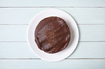 Aerial view of a whole chocolate fudge layer cake on a blue wooden table top background