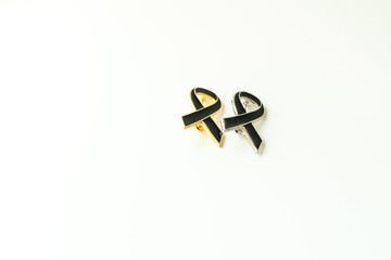 Condolences black ceramic ribbon on the pin with the wooden background. To show the sorrow with the grief on the passing of people. These ribbons can be pinned on shirts or clothes.