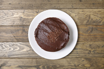 Aerial view of a whole chocolate fudge layer cake on a rustic wooden background