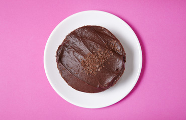 Aerial view of a whole chocolate fudge layer cake on a hot pink background