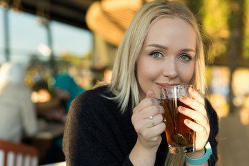 blond drinking coffee or tea in caffe shop