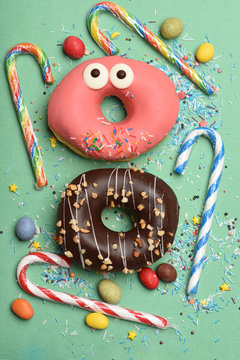Funny glazed donuts on green background