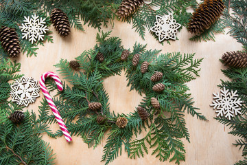 Naklejka premium Christmas composition from wreath, decor, candy cane, twigs cypress and snowflakes. Top view and copy space. Flat lay.