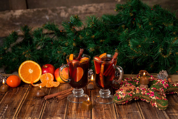 Christmas mulled wine with fruits and spices on wooden table. Xmas decorations in background. Two glasses. Winter warming drink  recipe ingredients around.