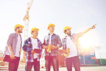 group of smiling builders with tablet pc outdoors