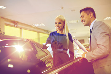 happy woman with car dealer in auto show or salon