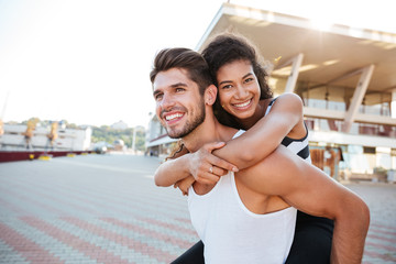 Man giving her girlfriend piggyback ride outdoors
