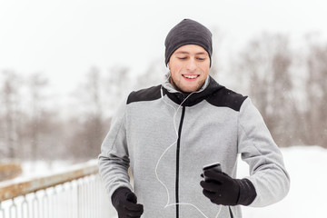 happy man with earphones and smartphone in winter
