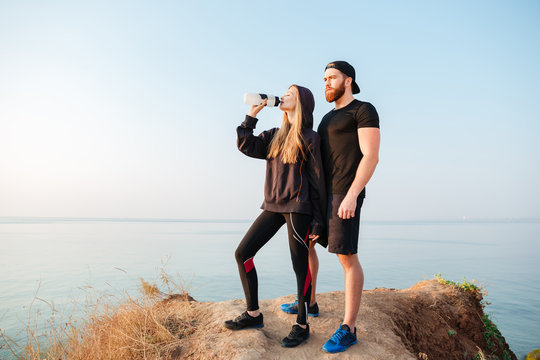 Young sports man and woman resting after jogging outdoors