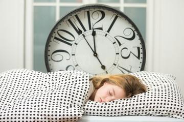Beautiful sleeping girl resting in bed with alarm clock , The sleeping teenager 
