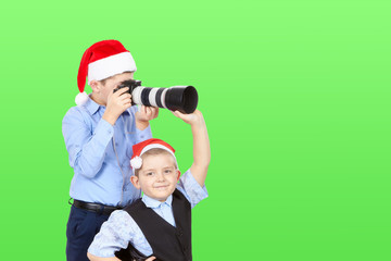 Little brother helping the brother is photographing on a green background