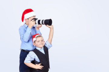 On the light background brothers are photographing in Santa Claus caps