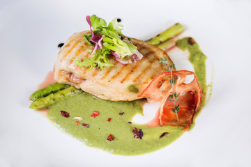 Grilled chicken breasts and vegetables on a plate with sauce