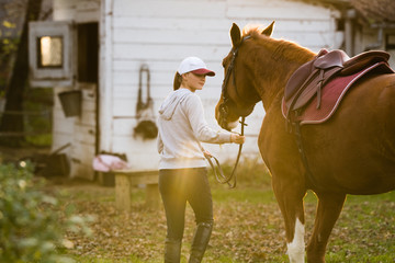Young girl preparing horse for ride