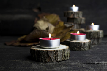 Christmas candles burning, decoration with wooden logs resting on rustic wooden background