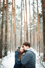 Couple in love having fun in winter forest