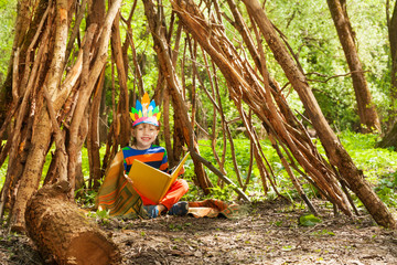 Happy boy reading stories of persons in wigwam