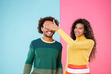 Happy young woman covered eyes of her boyfriend by hand