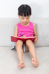 Asian Chinese little girl sitting on the sofa writting book