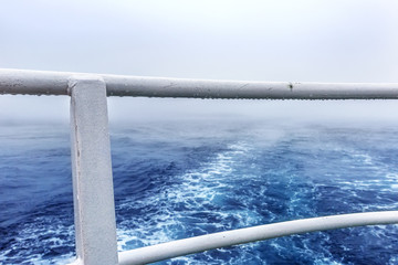 Trail on water surface behind of  ship in heavy fog
