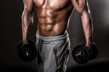 Fototapeta na wymiar Powerful Body of Athlete Bodybuilder Posing with Dumbbells