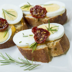 Small sandwiches with boiled eggs, dried tomatoes and rosemary