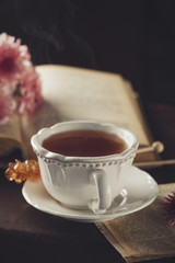Old retro book and cup of hot tea on old retro background, Selective focus. Toned Vintage style