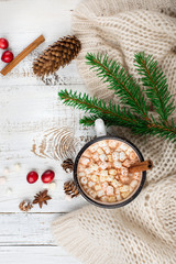 Fototapeta na wymiar Cup with homemade Christmas hot Chocolate drink, Marshmallows and knitted blanket on white wooden background. Winter time concept. Top view, flat lay style