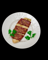Grill white fish fillet baked in bacon with parsley on a white plate isolated on white background