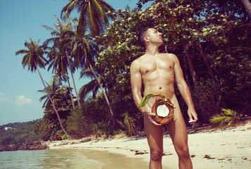 Naked man with coconut on the tropical beach. Thailand Koh Samui. Filter effect.