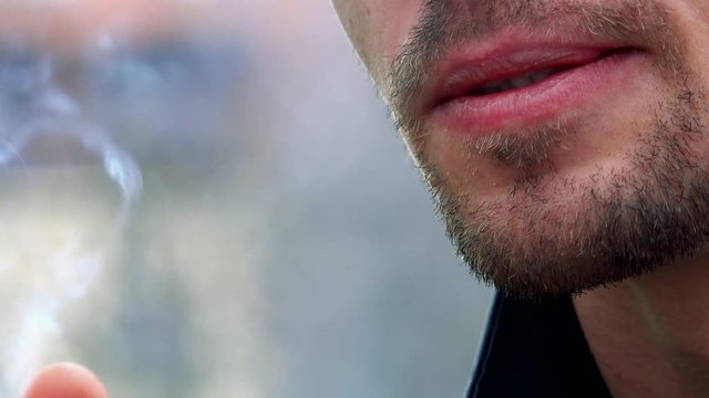 Young man smokes a cigarette - detail of mouth 